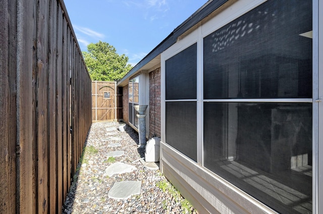 view of property exterior with brick siding, a sunroom, and fence