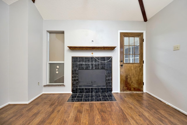 unfurnished living room featuring a fireplace, lofted ceiling with beams, wood finished floors, and baseboards