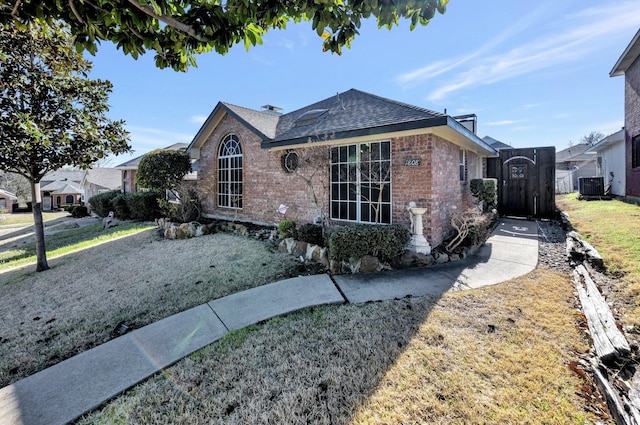 view of front of house with brick siding, central AC unit, a front lawn, and a shingled roof