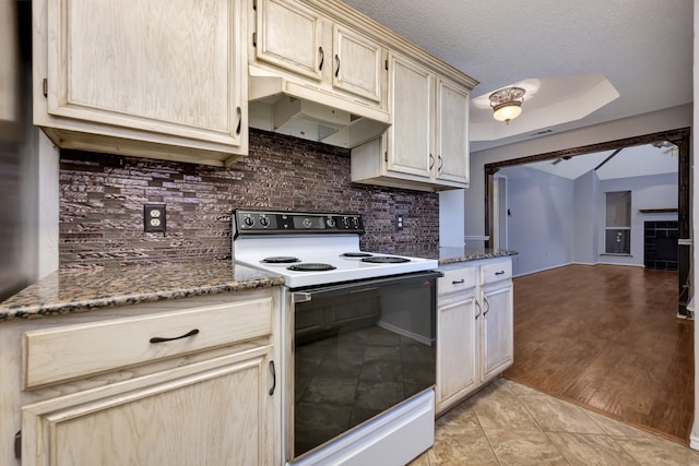 kitchen featuring light tile patterned floors, electric range oven, decorative backsplash, under cabinet range hood, and a textured ceiling