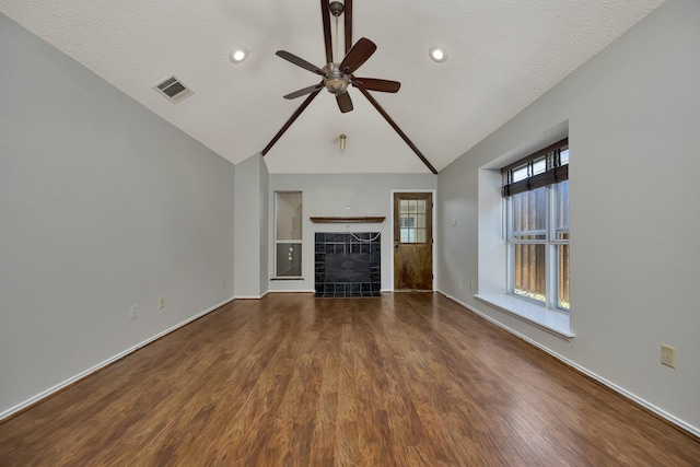 unfurnished living room with visible vents, a ceiling fan, a tile fireplace, wood finished floors, and vaulted ceiling