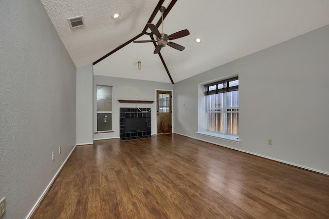 unfurnished living room with wood finished floors, visible vents, lofted ceiling, ceiling fan, and a tile fireplace