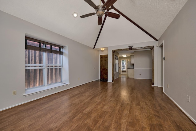 unfurnished living room with baseboards, lofted ceiling, dark wood-style floors, a textured ceiling, and a ceiling fan