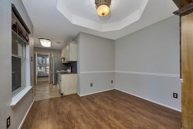 kitchen featuring stove, a textured ceiling, dark wood-type flooring, and a tray ceiling