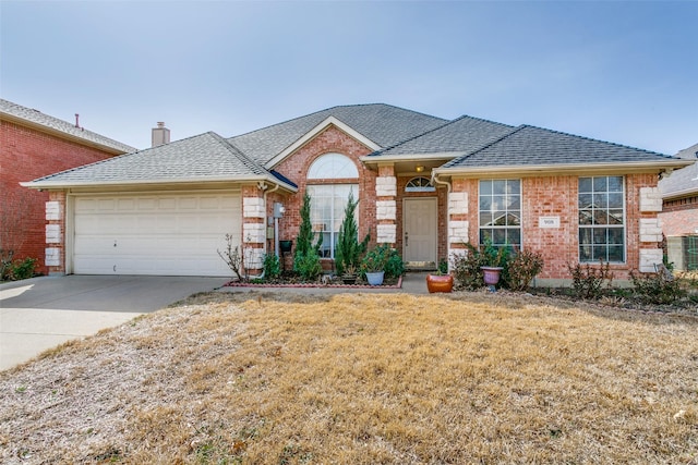 ranch-style home with brick siding, driveway, a shingled roof, and a front yard