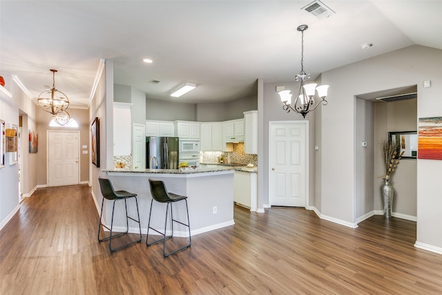 kitchen with a notable chandelier, white microwave, visible vents, and freestanding refrigerator