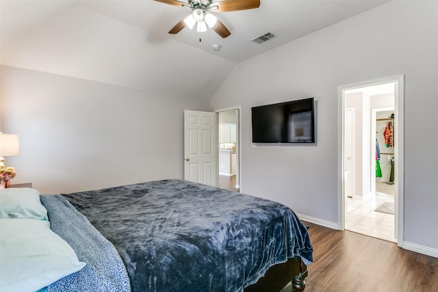 bedroom featuring a ceiling fan, wood finished floors, visible vents, baseboards, and lofted ceiling