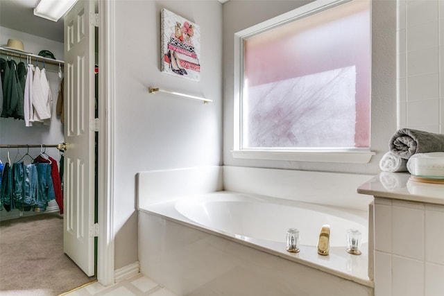 full bath with vanity, a garden tub, and a spacious closet