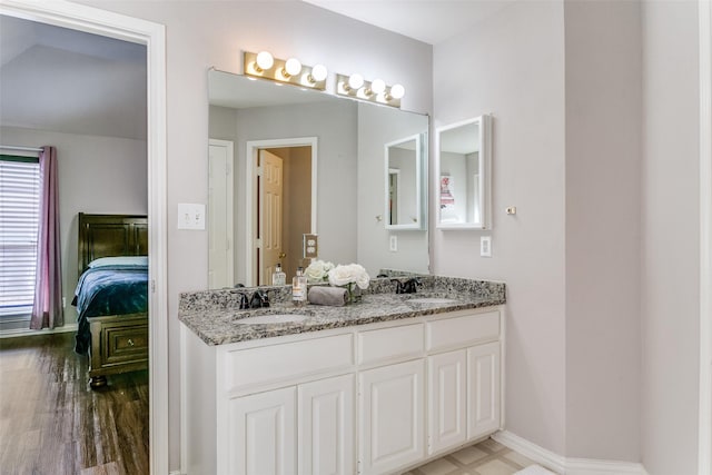 bathroom featuring a sink, baseboards, ensuite bath, and double vanity