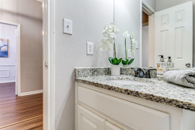 bathroom with baseboards, wood finished floors, and vanity