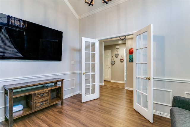 living room with french doors, crown molding, baseboards, and wood finished floors