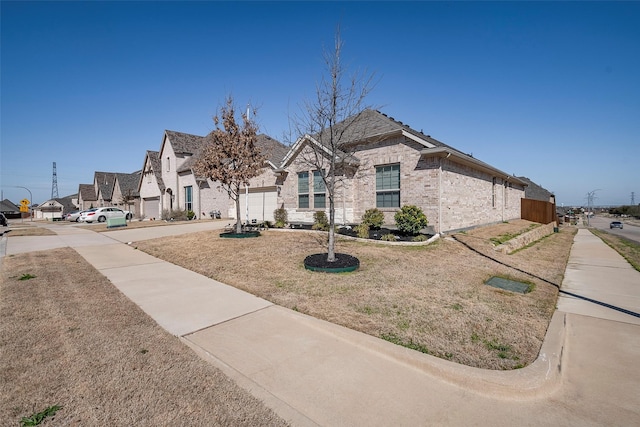 french country home with brick siding, a residential view, concrete driveway, and a garage