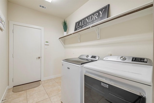 washroom with visible vents, baseboards, washing machine and dryer, light tile patterned floors, and laundry area