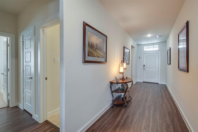 corridor featuring dark wood-style floors, visible vents, and baseboards