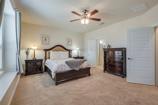 carpeted bedroom featuring visible vents, ceiling fan, and ensuite bathroom