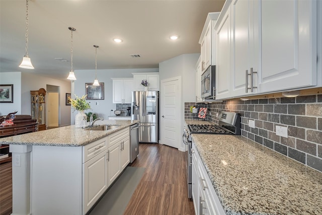 kitchen featuring dark wood finished floors, a center island with sink, decorative backsplash, appliances with stainless steel finishes, and white cabinets