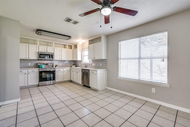 kitchen featuring visible vents, stainless steel appliances, light countertops, white cabinets, and tasteful backsplash