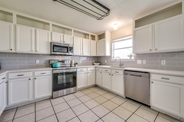 kitchen featuring a sink, stainless steel appliances, backsplash, and white cabinetry