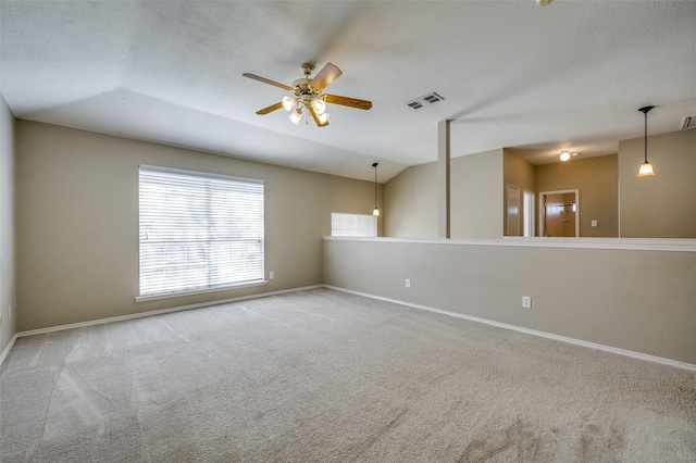 empty room featuring visible vents, lofted ceiling, baseboards, and carpet flooring