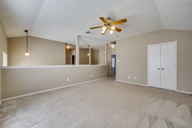 carpeted spare room featuring lofted ceiling, baseboards, visible vents, and ceiling fan