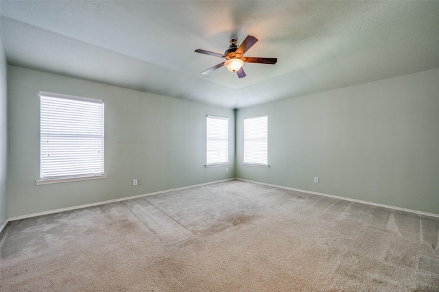 carpeted empty room featuring baseboards and a ceiling fan