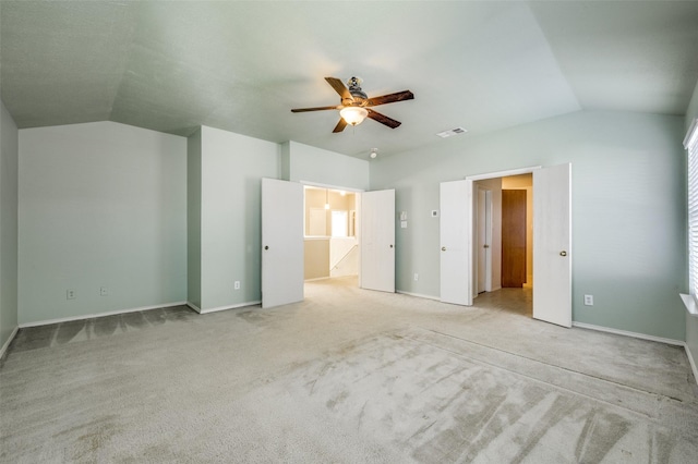 unfurnished bedroom featuring baseboards, visible vents, lofted ceiling, ceiling fan, and light colored carpet