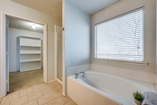 bathroom with a shower stall, a garden tub, and tile patterned floors