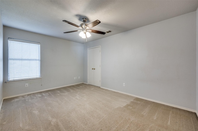 carpeted spare room featuring visible vents, a textured ceiling, baseboards, and a ceiling fan