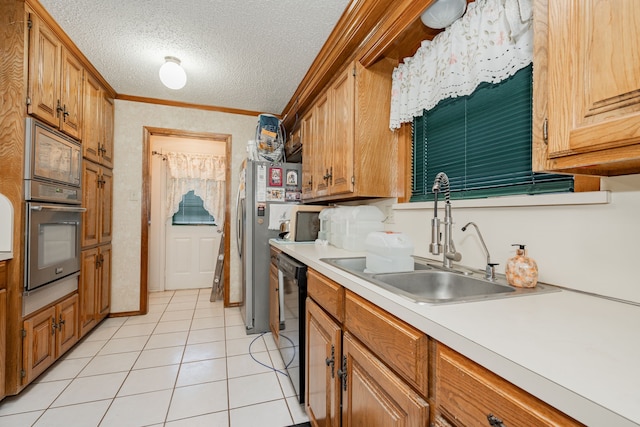 kitchen featuring light countertops, stainless steel appliances, light tile patterned flooring, a textured ceiling, and a sink