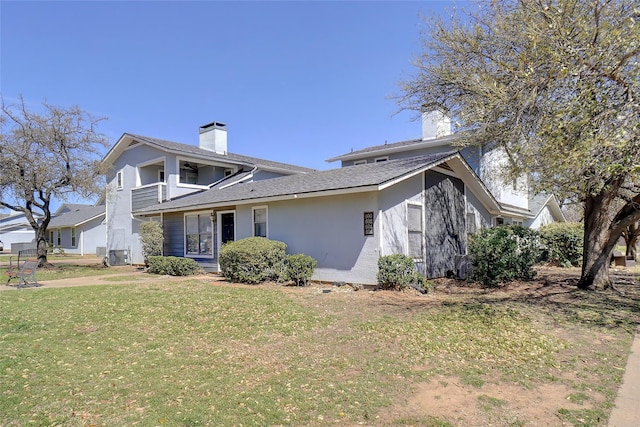 view of front of property with a chimney, stucco siding, and a front lawn