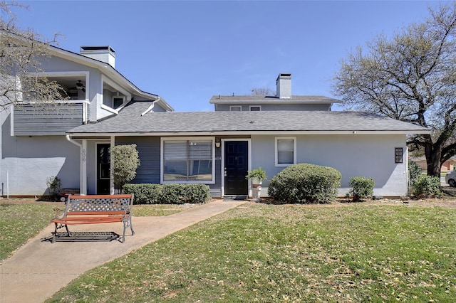 view of front of property featuring a front lawn, stucco siding, and a chimney
