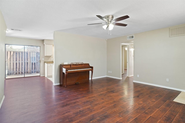 empty room featuring visible vents, a ceiling fan, and wood finished floors