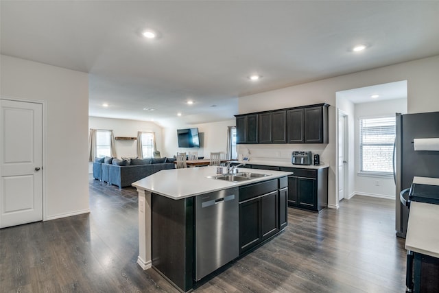 kitchen with a kitchen island with sink, a sink, stainless steel appliances, dark wood-type flooring, and a wealth of natural light