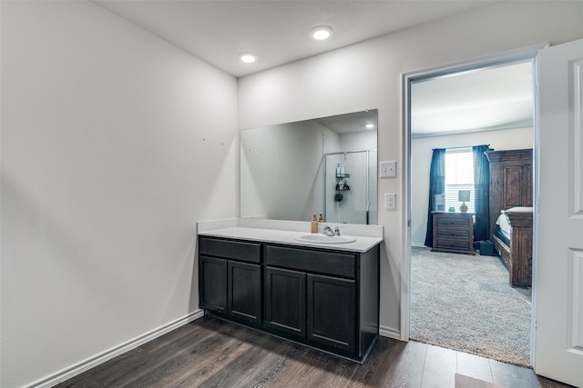 ensuite bathroom with vanity, wood finished floors, and baseboards