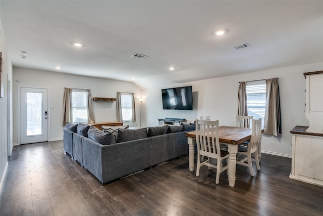 living room with dark wood-style floors, visible vents, and a healthy amount of sunlight