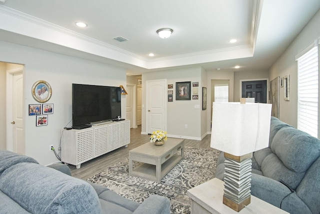 living area with visible vents, a tray ceiling, and wood finished floors