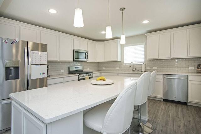 kitchen featuring a sink, tasteful backsplash, a kitchen island, white cabinetry, and stainless steel appliances