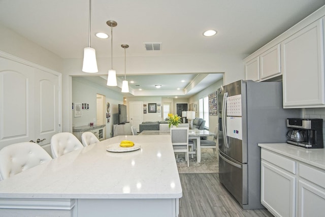 kitchen featuring visible vents, open floor plan, light wood-type flooring, freestanding refrigerator, and white cabinets