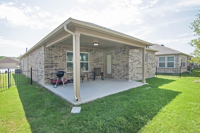 back of house featuring brick siding, a yard, a patio area, and fence