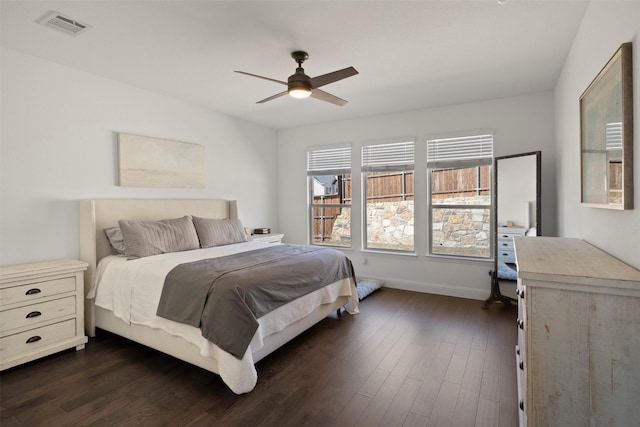 bedroom featuring ceiling fan, visible vents, baseboards, and dark wood-style floors