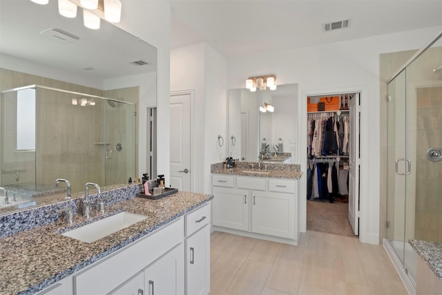 full bathroom with visible vents, a shower stall, and a sink