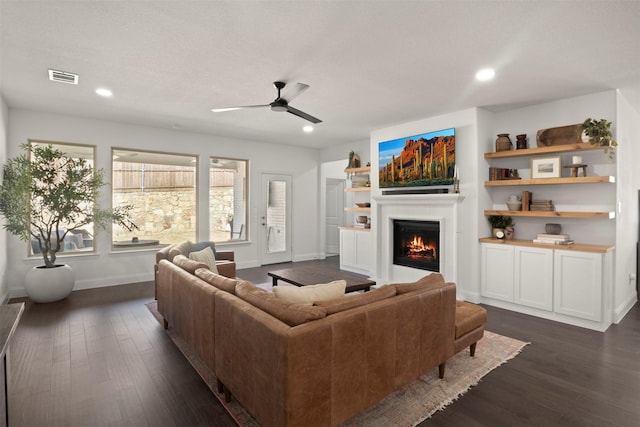 living room featuring visible vents, recessed lighting, a lit fireplace, and dark wood-style flooring