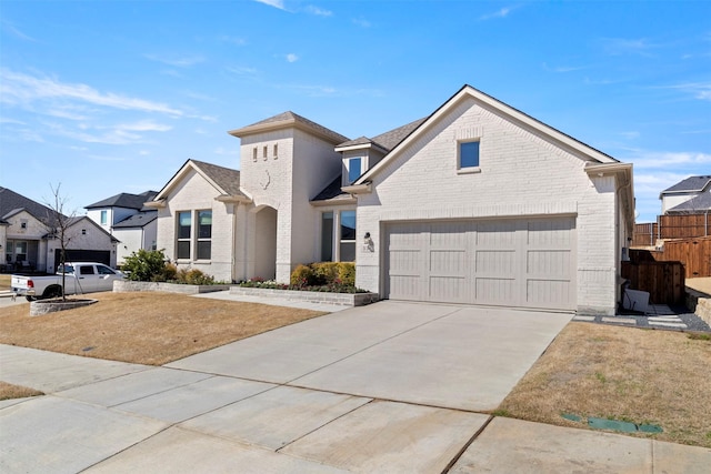 view of front of home featuring a garage, fence, brick siding, and driveway