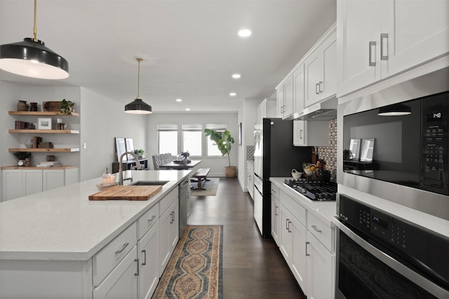 kitchen featuring tasteful backsplash, under cabinet range hood, light countertops, dark wood-style floors, and stainless steel appliances