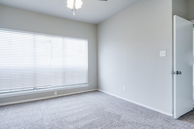 carpeted spare room with a ceiling fan and baseboards