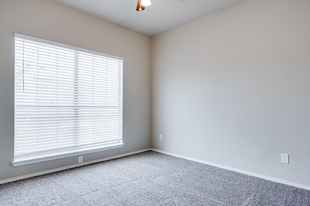 carpeted spare room featuring a healthy amount of sunlight, baseboards, and ceiling fan