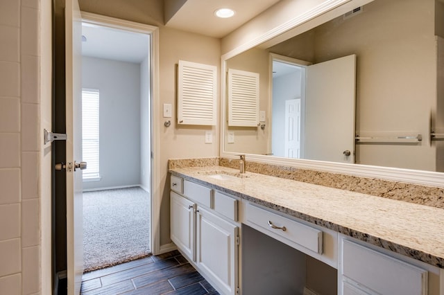 bathroom with wood finish floors, visible vents, recessed lighting, baseboards, and vanity