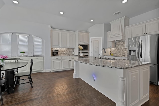 kitchen with dark wood finished floors, custom range hood, stainless steel appliances, white cabinetry, and a sink