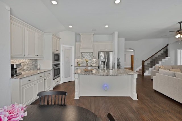 kitchen featuring open floor plan, dark wood-style floors, arched walkways, and stainless steel appliances