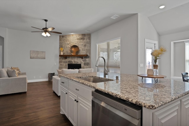 kitchen featuring a sink, light stone counters, open floor plan, a stone fireplace, and dishwasher